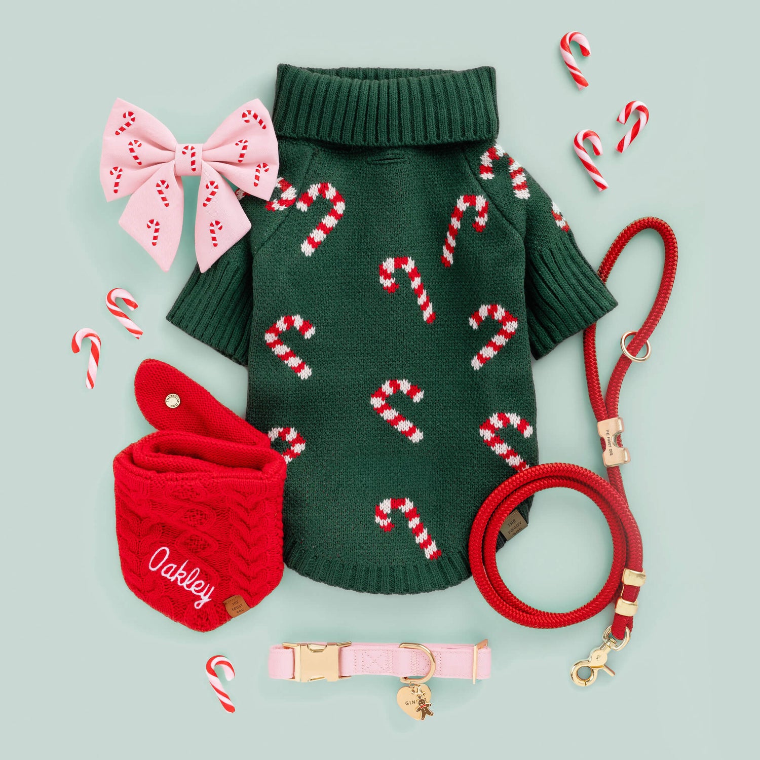 Evergreen Candy Canes Dog Sweater, Blush Pink Candy Canes Lady Bow, Ruby Marine Rope Leash, Cable Knit Bandana, Blush Pink Collar, Heart ID Tag, and Gingerbread Man Charm from The Foggy Dog